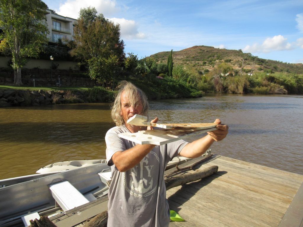 A man showing how a piece of wood has been bent by the weight of anchor chain