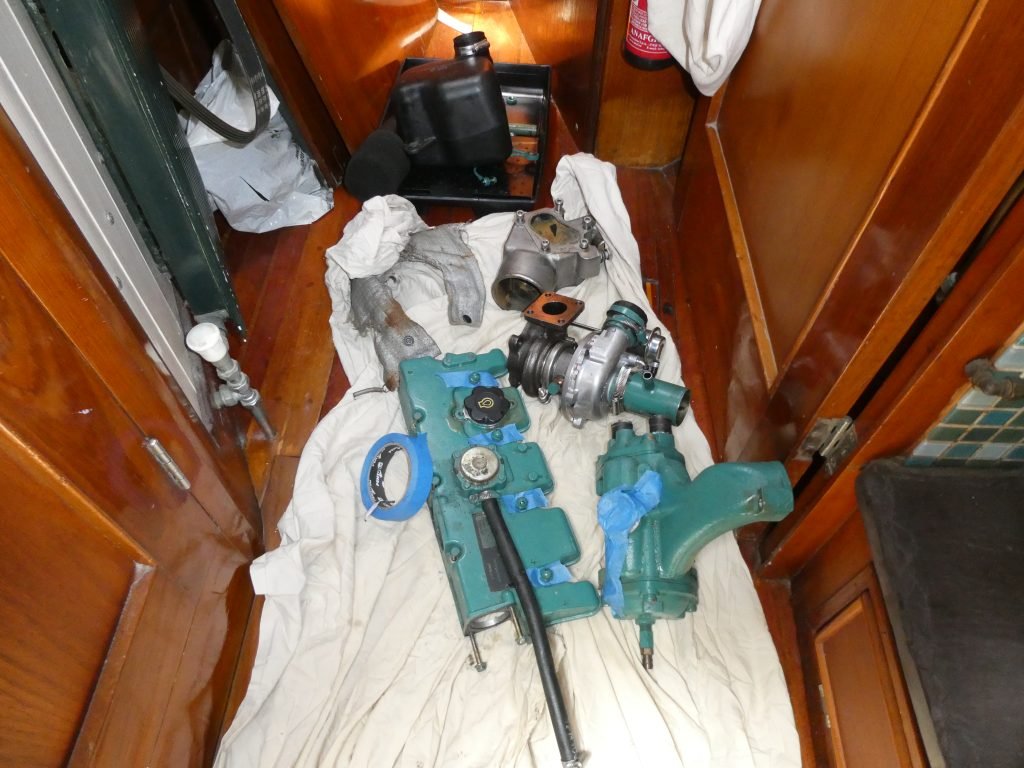 components of a broken engine gathering on the floor of a sail boat