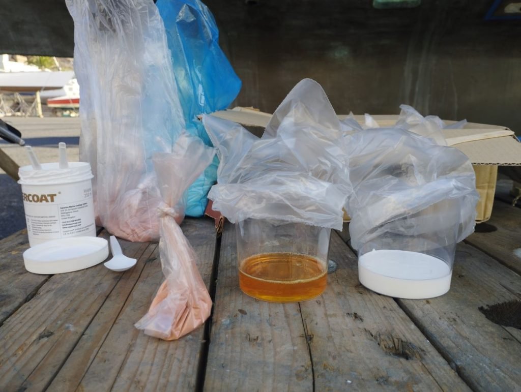 A bag of copper alongside two plastic pots containing an orange liquid and a white liquid