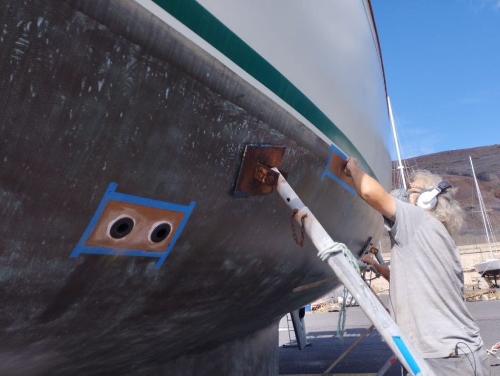 A man preparing for painting Coppercoat onto a boat's hull